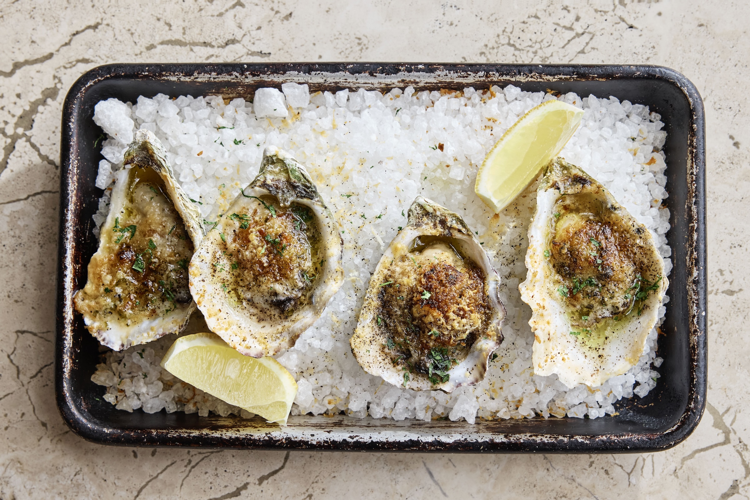 a tray of oysters with lemon wedges