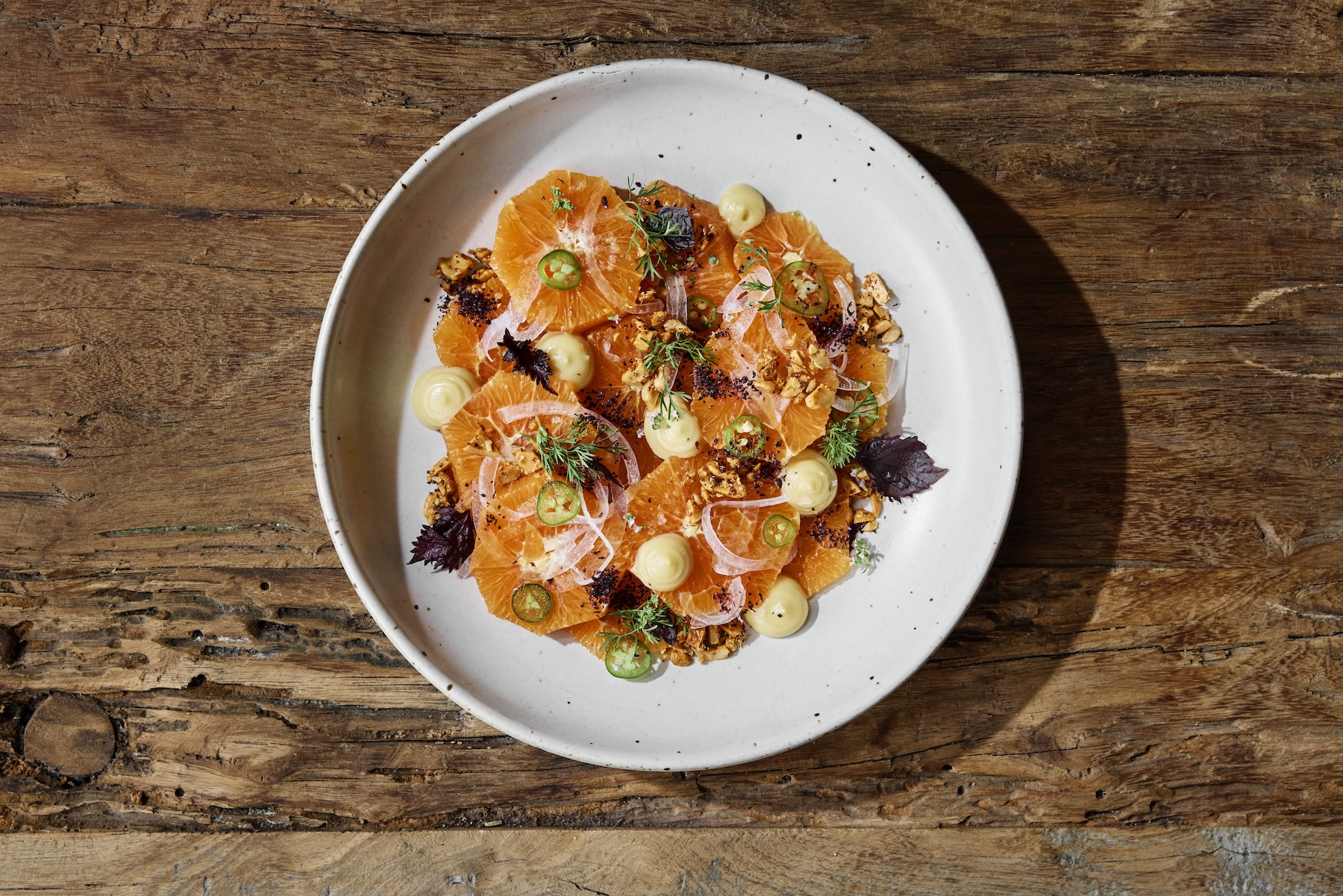 Bowl of orange and walnut salad on wooden table