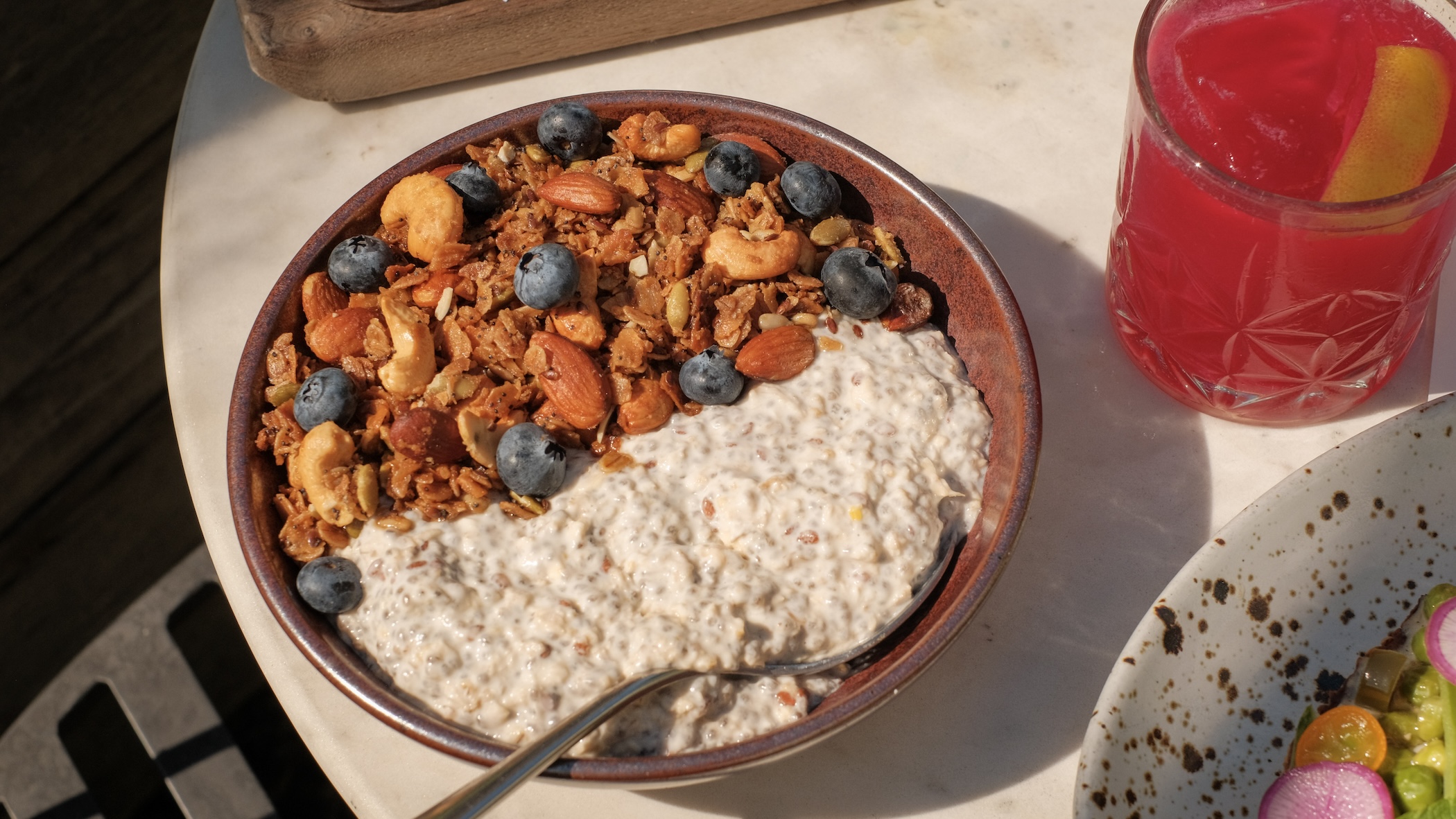 A brown shallow bowl with brown granola, blue berries, and white yogurt-like mixture
