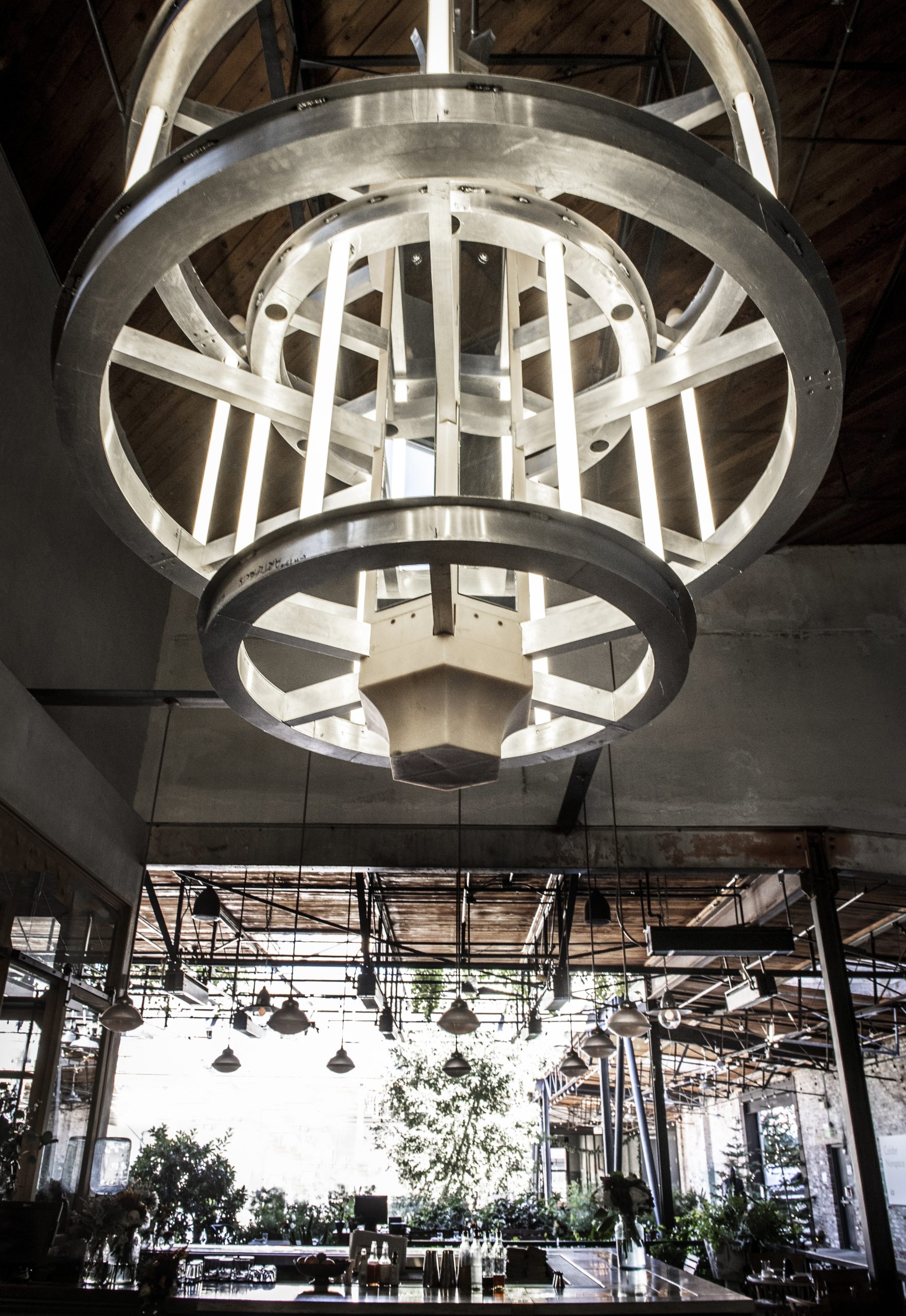 A lighting fixture in Manuela hanging from the ceiling. Fixture is made up of metal circles with long strips of light connecting them. Art detail: Paul McCarthy (b. 1945) Crown 2003 Aluminium, fluorescent tubes, mirrors, wood