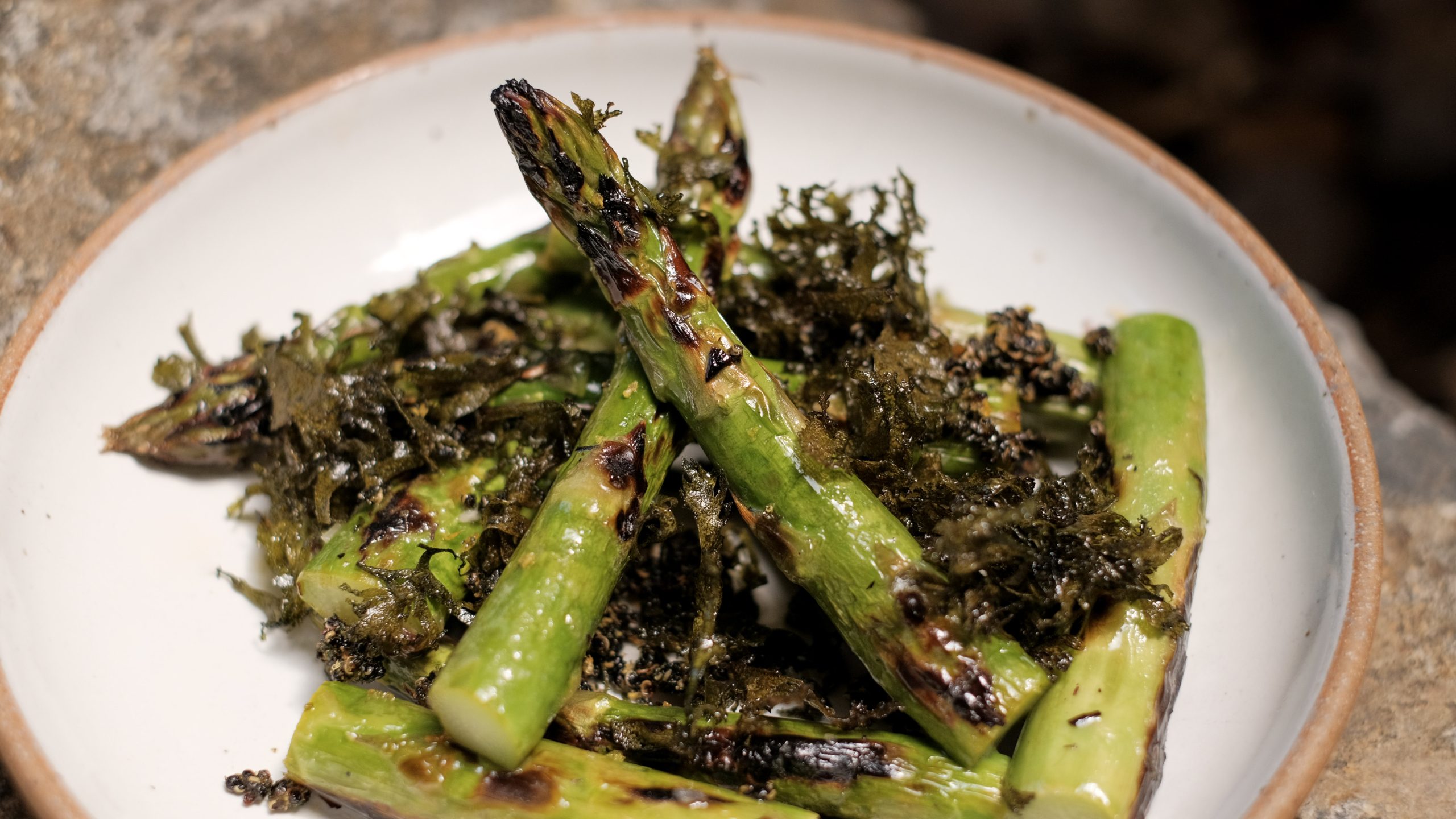 Pieces of grilled green asparagus on a white plate.