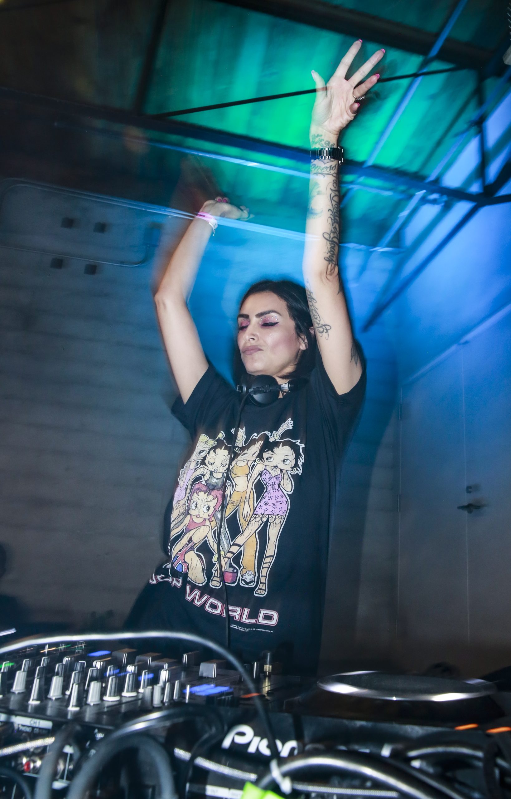 Woman DJ in a black shirt with her hands raised dancing.
