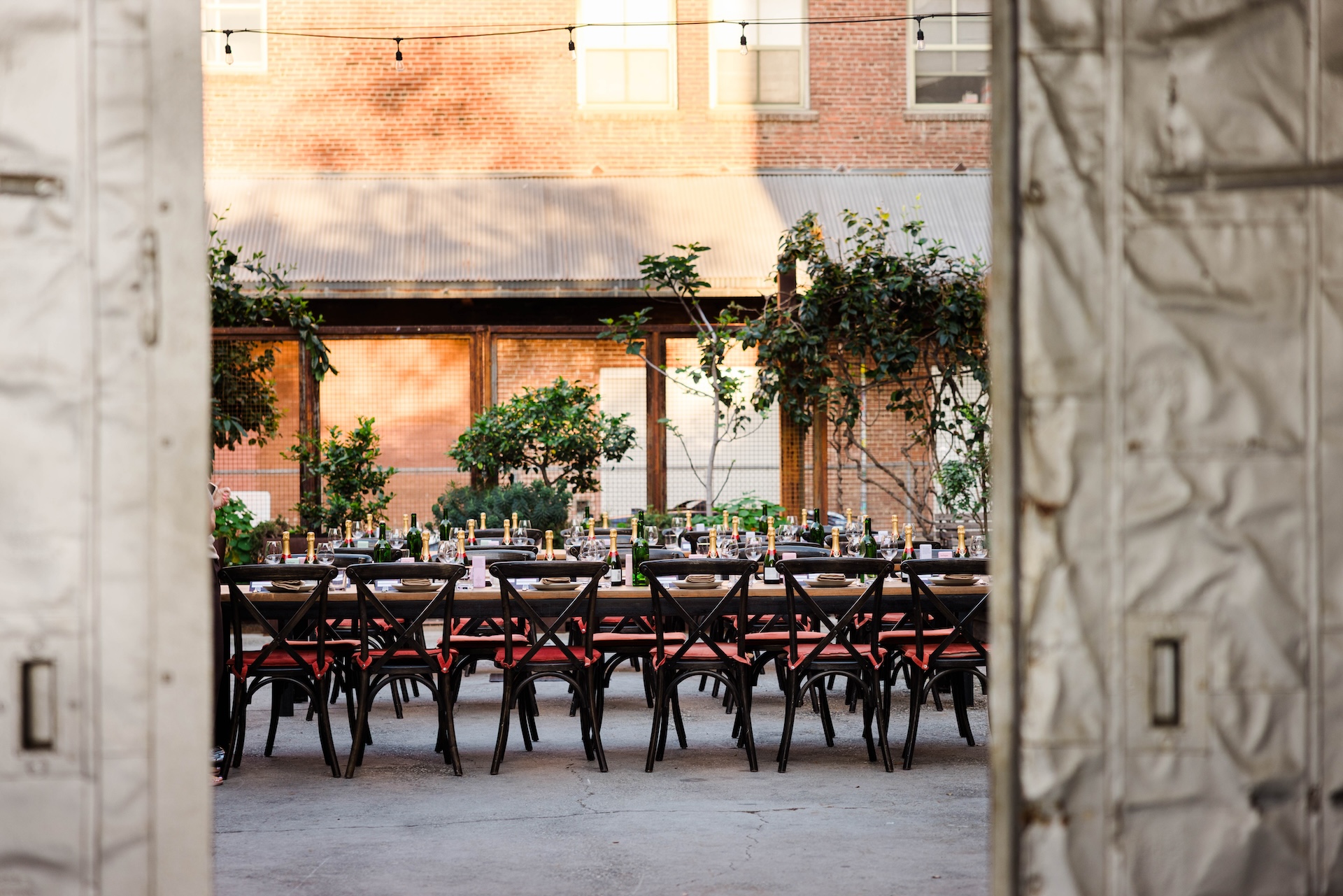 Two metal doors framing a row of seats around a long table set for a private dinner.