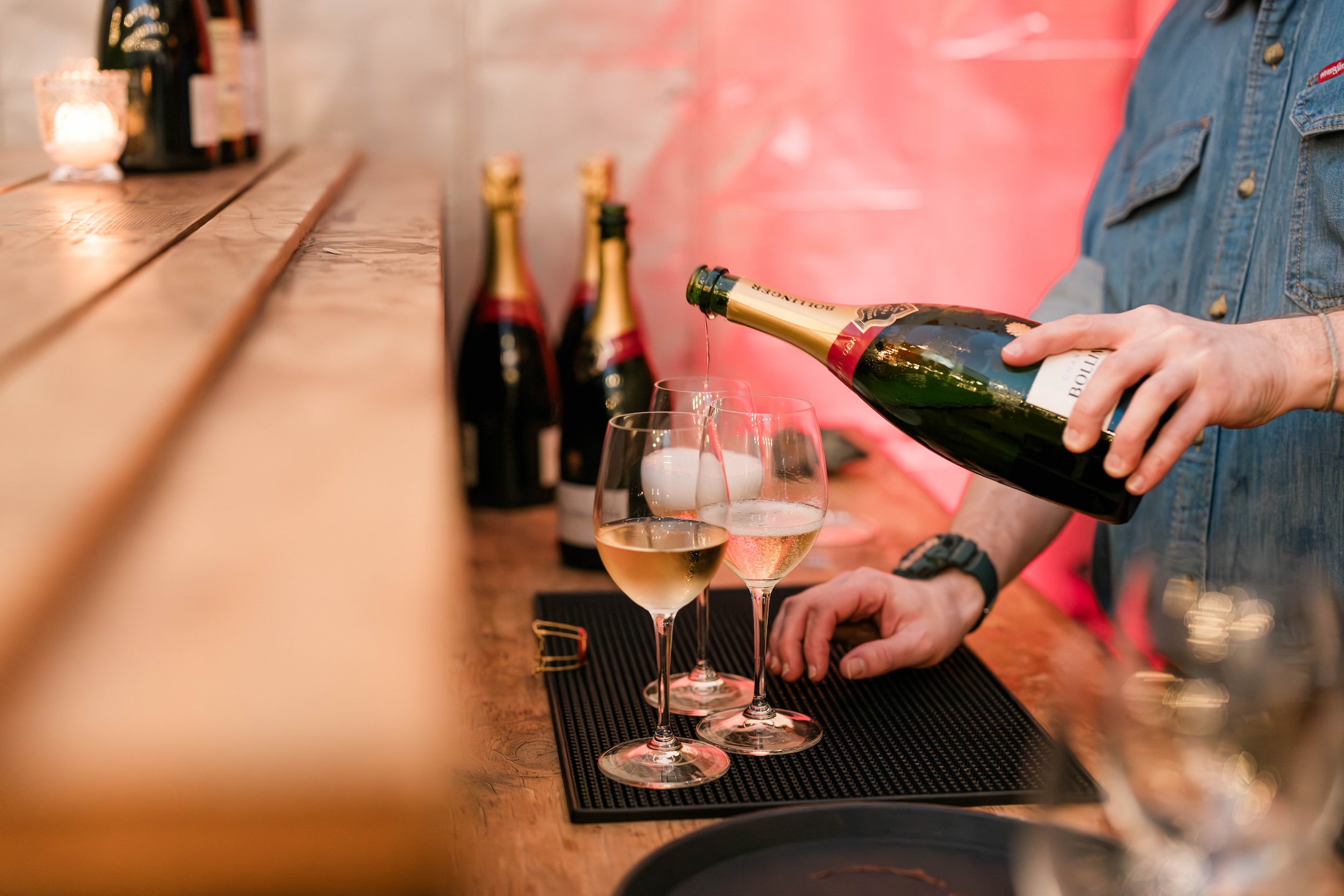 Hand pour rose sparkling wine into a wine glass from behind the bar.
