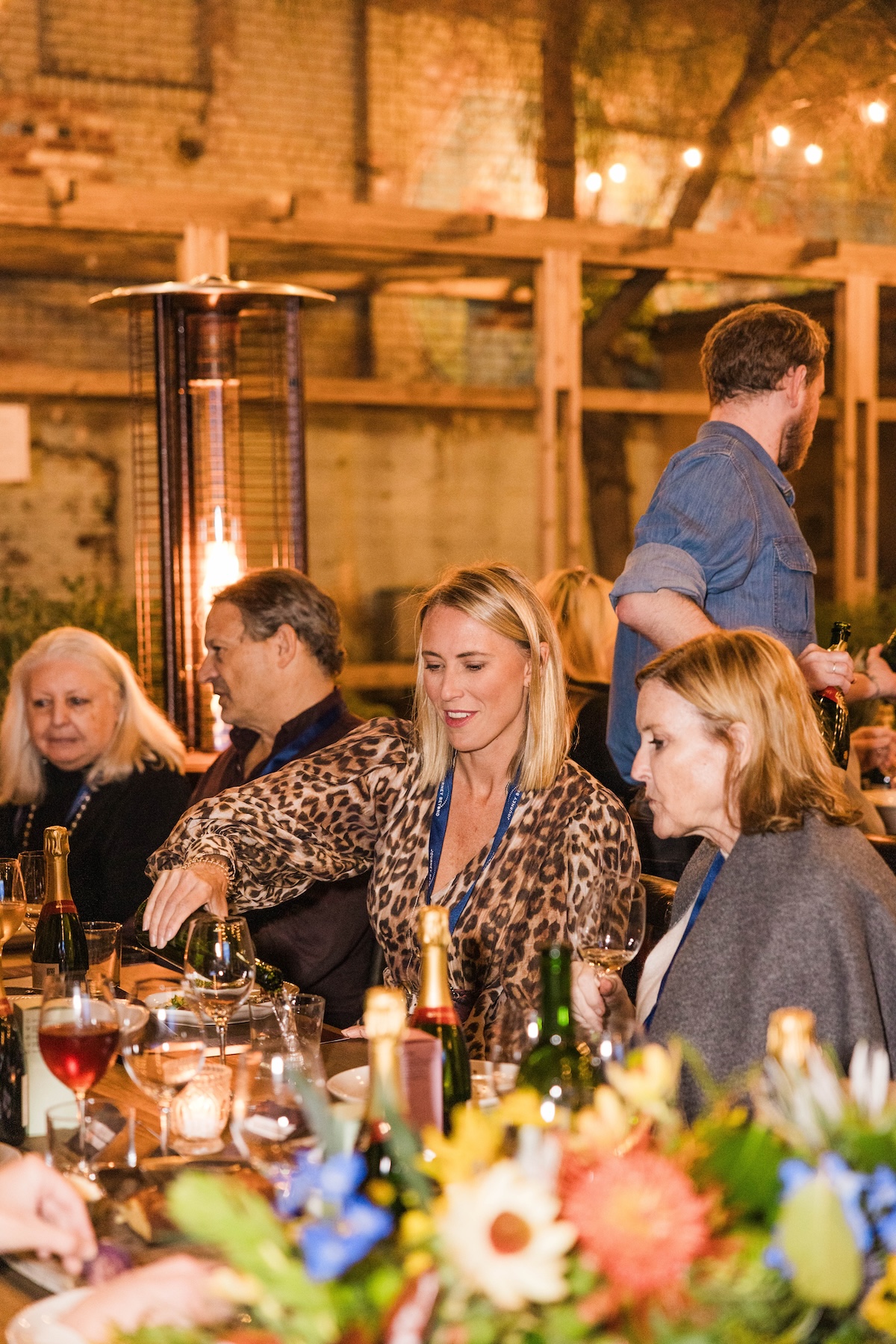 A group of people eating outside during an event with outdoor heaters.