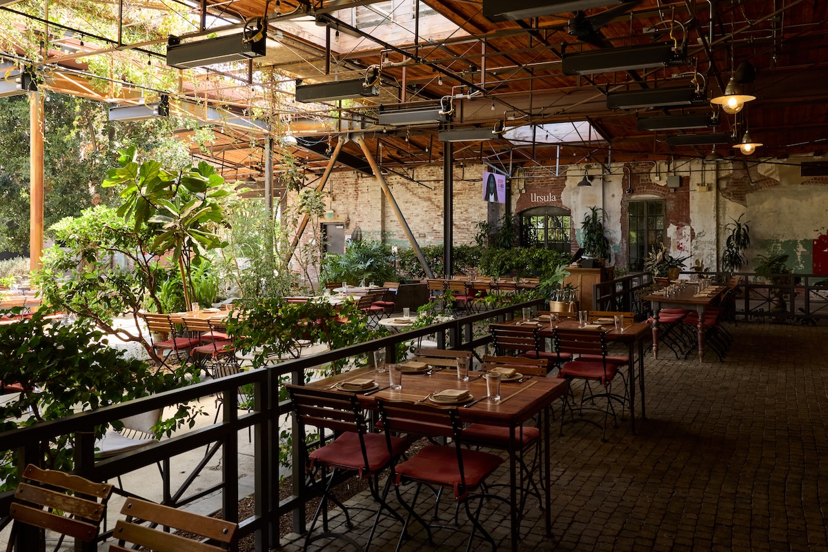 An exterior shot of Manuela's courtyard area, partially covered by a roof. Tables and chairs are set for dining.