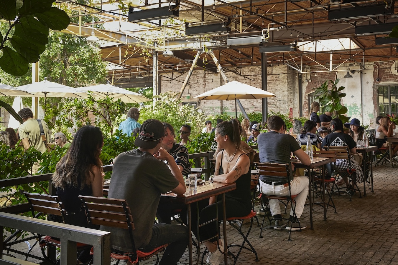People sitting at at outdoor tables talking and enjoying a meal.