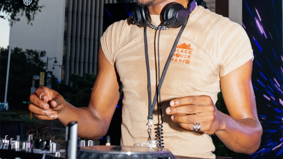 Man's torso with headphones around their neck and a DJ turntable in front of them